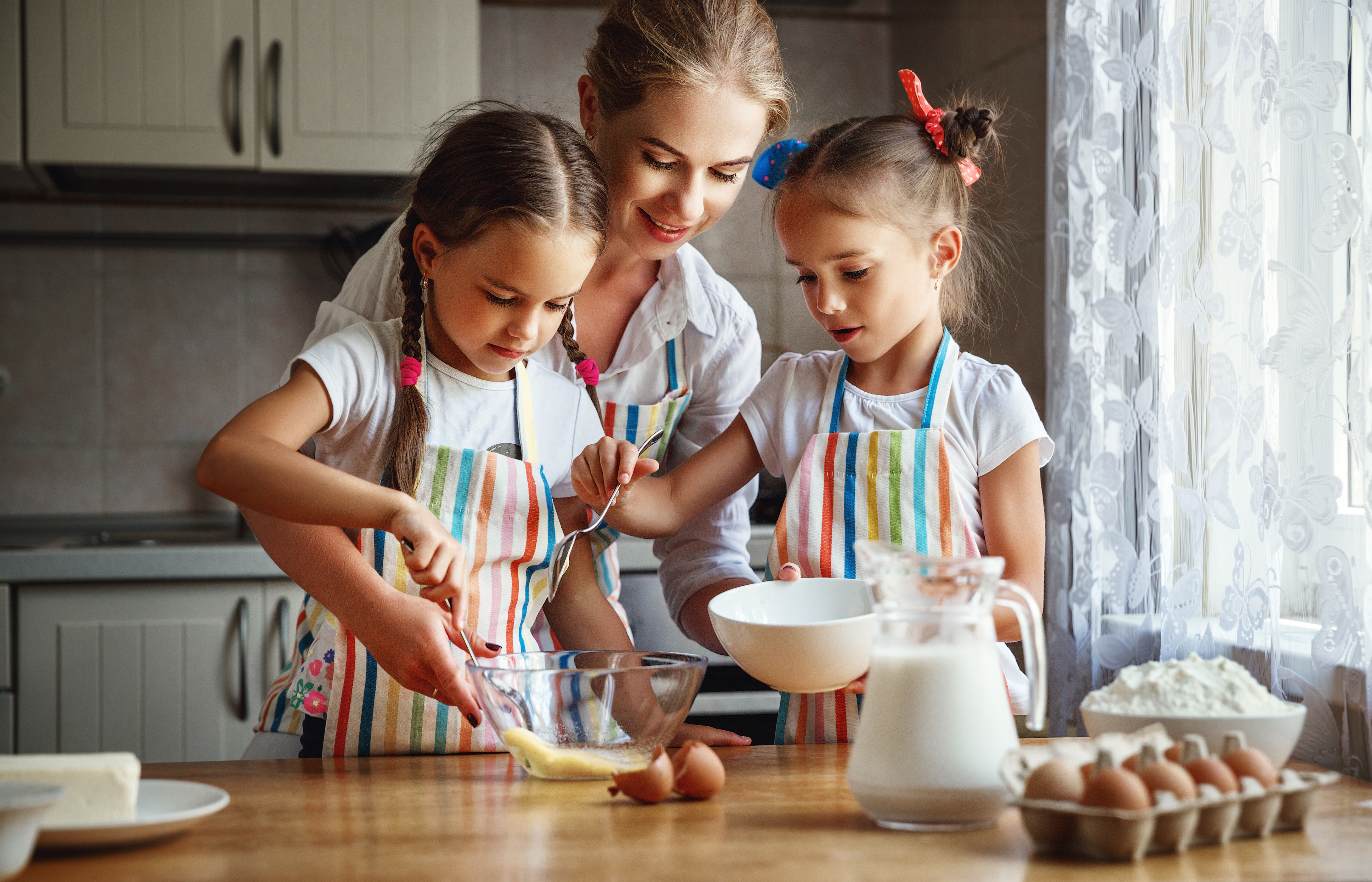 A mother with her two daughters baking cakes in their kitchen