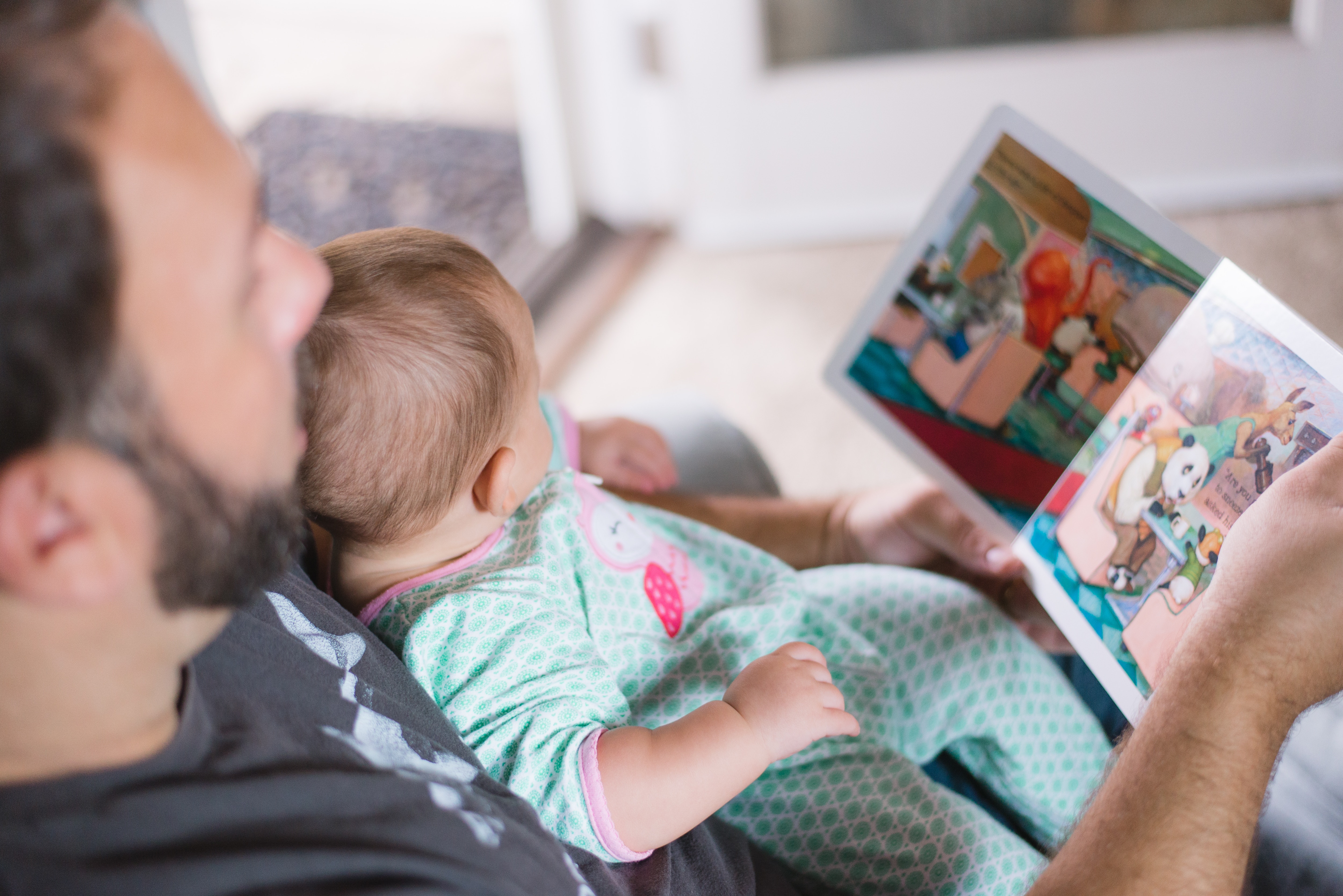 A father sat with his baby on his lap reading a story book