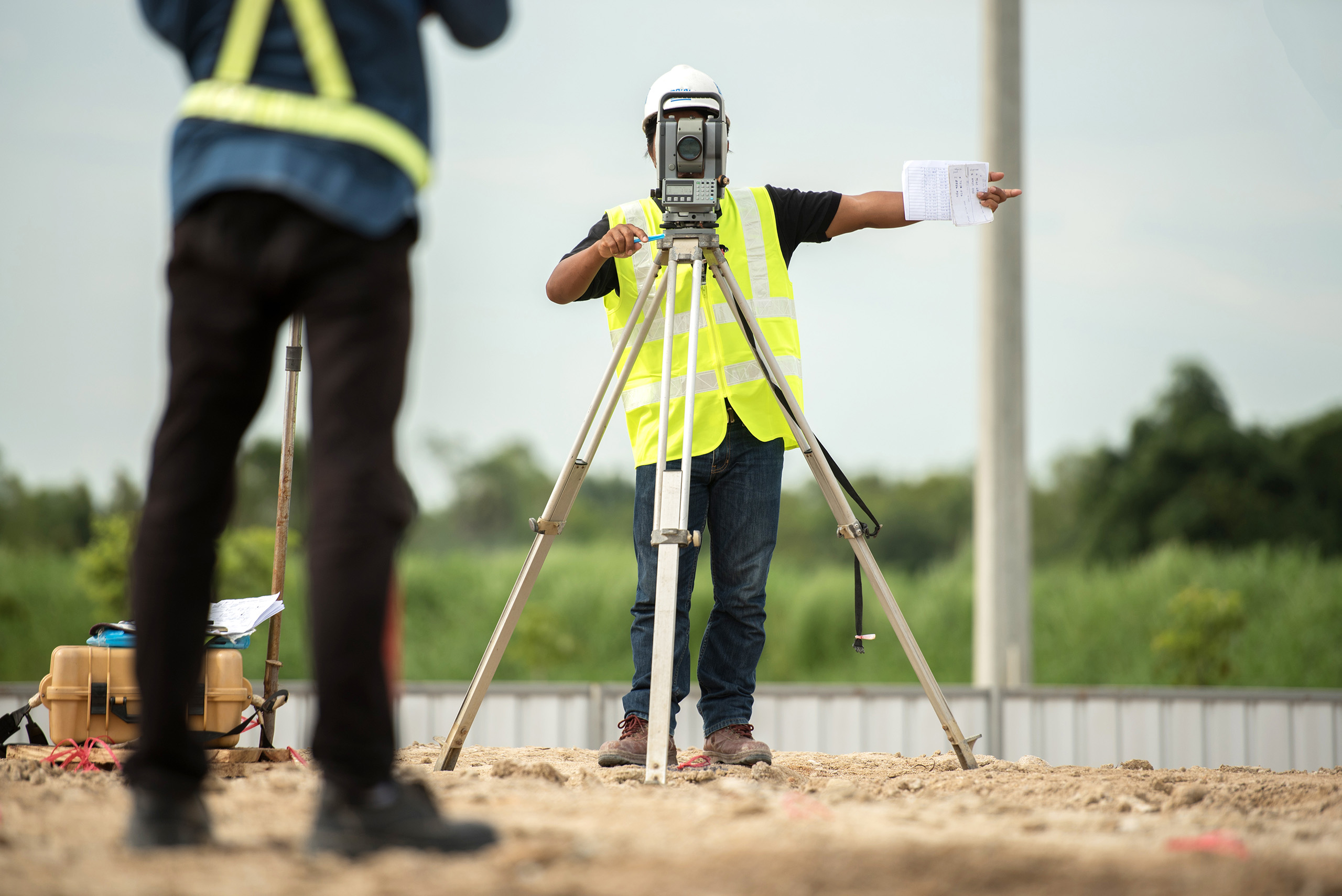 A planning and development surveyor taking measurements on new building plot