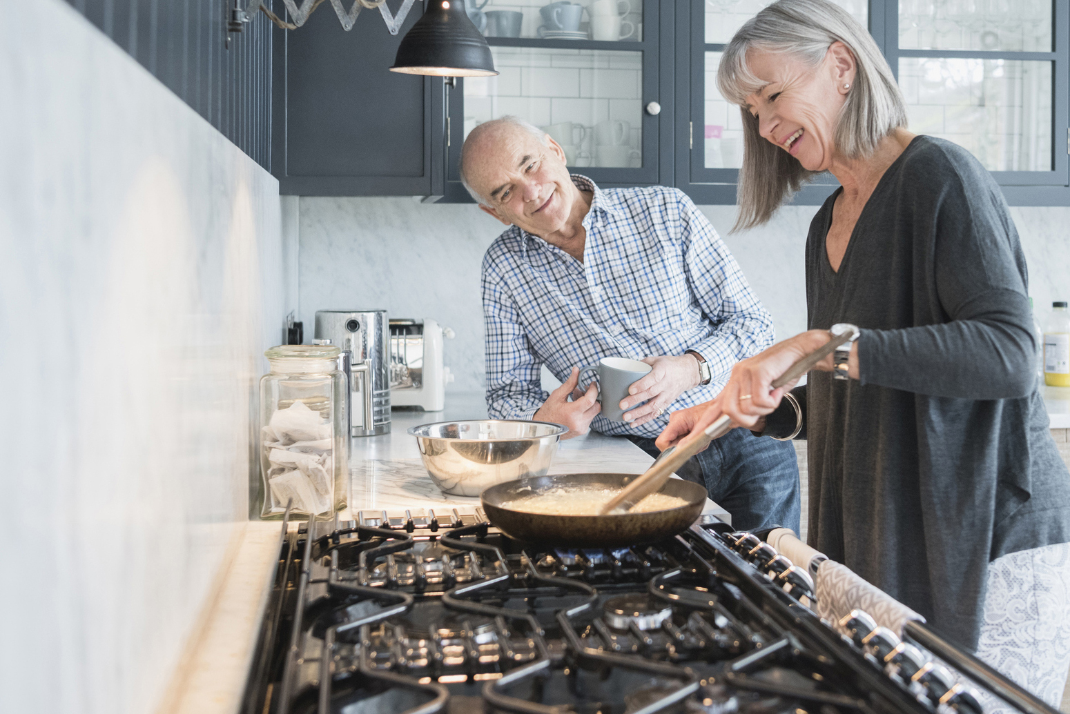 A middle-aged couple talking and cooking in their kitchen